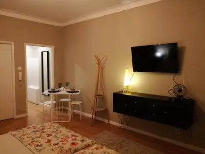 a living room with a television on a wall with a table at Pontocom Bolhão Apartment in Porto