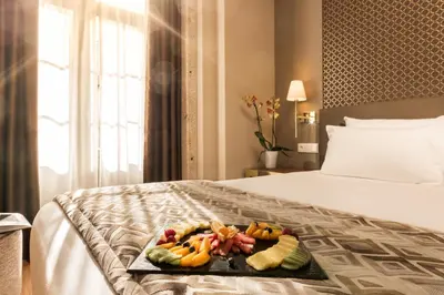 a tray of fruit on a bed in a hotel room at Exe Almada Porto in Porto