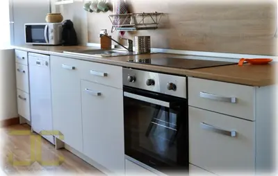 a kitchen with white cabinets and a black oven at Country Apartment by JC in Porto
