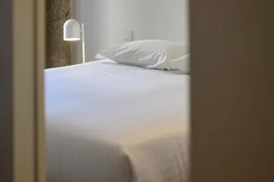 a bed with white sheets and pillows in a room at Pause Apartments in Porto
