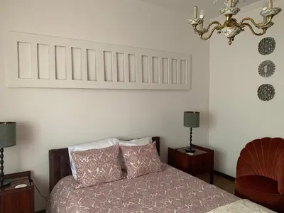 a bedroom with a bed and a chandelier at A Casa das Margaridas in Porto