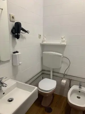 a white bathroom with a toilet and a sink at A Casa das Margaridas in Porto
