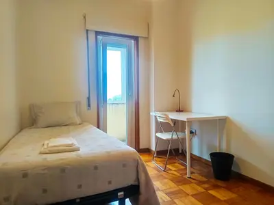 a bedroom with a bed and a desk and a window at Combatentes Apartment in Porto