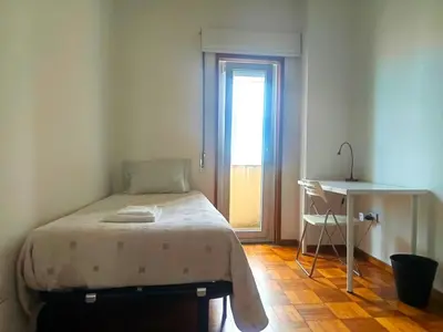 a bedroom with a bed and a table and a window at Combatentes Apartment in Porto