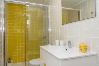 a bathroom with a sink and a shower with yellow tiles at Porto City Center 2 in Porto
