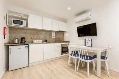 a kitchen with white cabinets and a table and chairs at BRA.com Apartments Oporto Campanhã in Porto