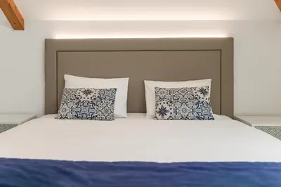 a bed with blue and white pillows on it at BRA.com Apartments Oporto Campanhã in Porto