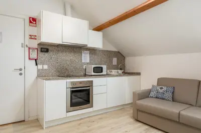 a kitchen with white cabinets and a couch at BRA.com Apartments Oporto Campanhã in Porto