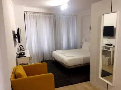 a bedroom with a bed and a chair and a mirror at Koka's Studio in Porto