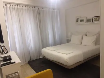 a bedroom with a white bed with white curtains at Koka's Studio in Porto