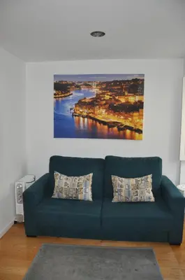 a blue couch in a living room with a painting on the wall at KOKAS Apartments in Porto