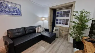 a living room with a black leather couch and a window at Merc Porto Ribeira's View in Porto