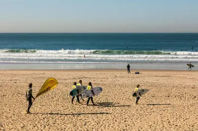 a group of people walking on the beach with surfboards at Merc Porto Ribeira's View in Porto