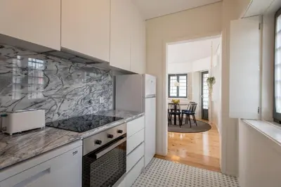 a kitchen with white cabinets and marble counter tops at Oporto Serviced Apartments - Alvares Cabral in Porto