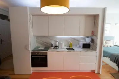 a small kitchen with white cabinets and a microwave at OPorto Histórico - Galerias in Porto