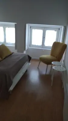 a bedroom with a bed and a chair and two windows at Downtown Porto Mouzinho Studio Apts in Porto