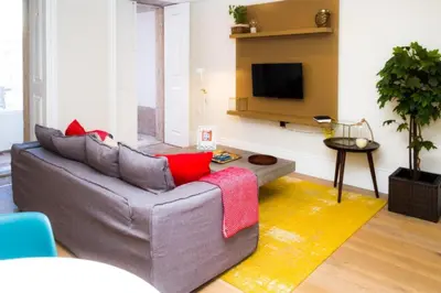 a living room with a grey couch and a tv at Liiiving in Porto | Central Garden Flat in Porto