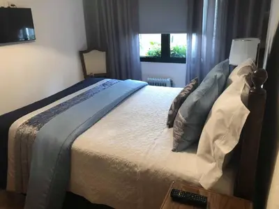 a bedroom with a large bed with a remote control at Alojamento Requinte in Porto