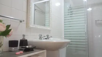 a white bathroom with a sink and a mirror at Alojamento Requinte in Porto