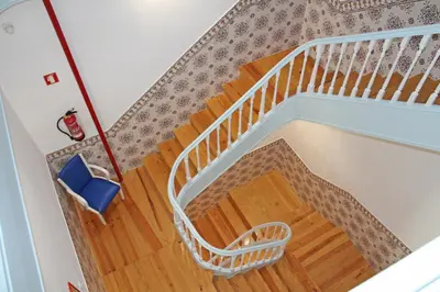 a spiral staircase with a white rail and wooden floors at Grande Oceano Guest House in Porto