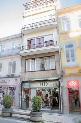 a tall building on a city street with a store at Travel & Live Hostel in Porto