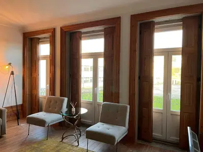 a living room with two chairs and a table and windows at Go2oporto - Fontainhas Apartments in Porto