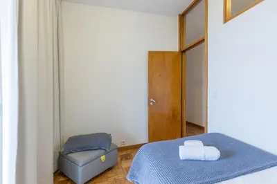 a bedroom with a blue bed and a chair at BEST - Trindade Tower in Porto