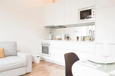 a white living room with a white couch and a kitchen at Zelije Apartments Trindade in Porto