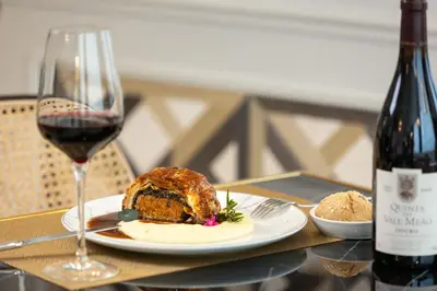a table with a plate of food and a glass of wine at Hotel Cristal Porto in Porto