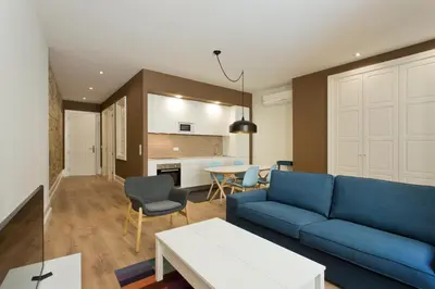 a living room with a blue couch and a kitchen at RVA - Clerigos Apartments in Porto