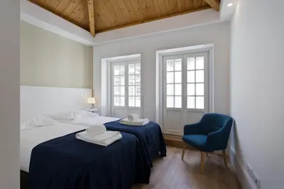 a bedroom with two beds and a blue chair at RVA - Clerigos Apartments in Porto