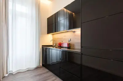 a kitchen with black cabinets and a red appliance at LETHESHOME Apartments in Porto