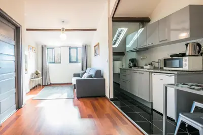 a kitchen with stainless steel appliances and a living room at Apartamento À Francos Attic in Porto