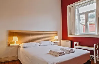 a bedroom with a bed with red walls and a window at Porto Spot Hostel in Porto