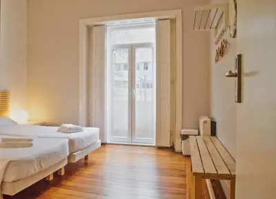 a bedroom with two beds and a sliding glass door at Porto Spot Hostel in Porto