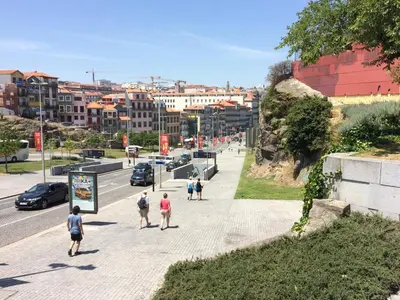 a group of people walking down a sidewalk next to a street at Downtown PORTO SE in Porto