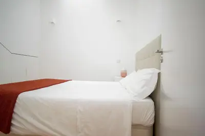 a bedroom with a bed with white sheets and red blanket at CL Fernandes Tomás I in Porto