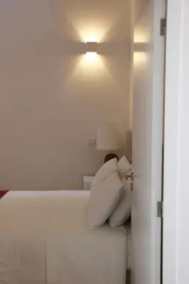 a bedroom with a white bed and a lamp at CL Fernandes Tomás I in Porto