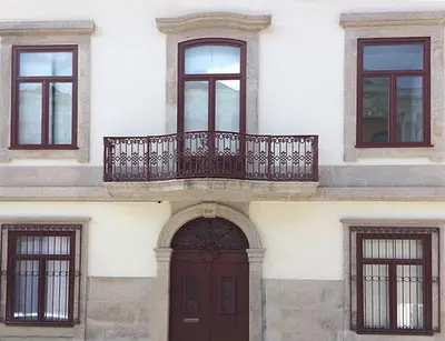 a building with a wooden door and a balcony at CL Fernandes Tomás I in Porto