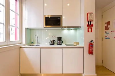 a kitchen with white cabinets and a microwave at São Bento Golden Flat in Porto