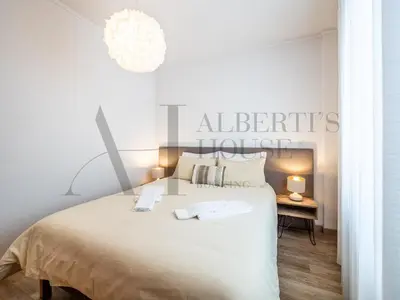 a white bedroom with a large bed and a chandelier at Alberti's House Oporto Central Apartment in Porto