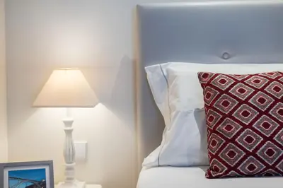 a bed with a red pillow next to a lamp at Modern loft w AC Downtown and Metro in Porto