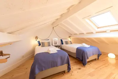 two beds in a attic room with a window at LovelyStay - Top Floor Balcony Apartment in Porto