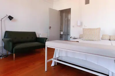 a living room with a bed and a green chair at Pensao Favorita in Porto
