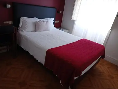a hotel room with three beds and a window at Hotel Paulista in Porto