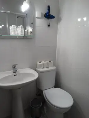 a white bathroom with a toilet and a sink at Hotel Porto Rico in Porto