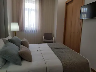 a bedroom with a bed with pillows and a television at 22 Oporto Guesthouse in Porto