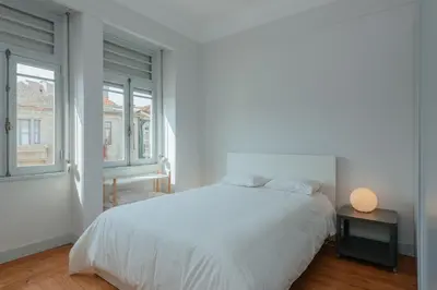 a white bedroom with a bed and two windows at Baixa24 - Downtown Bliss w/ Amazing Natural Light in Porto
