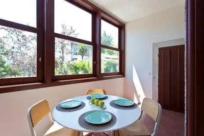 a dining room with a table and chairs and windows at Trait House in Porto