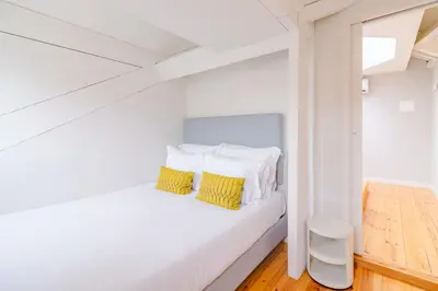 a white bedroom with a bed with yellow pillows at YOUROPO - City Center Ribeira Porto in Porto